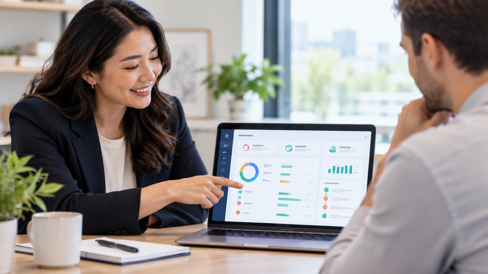 Writing Professional explaining income and expenditure assessment software to a colleague, using a laptop displaying financial dashboards and performance data.